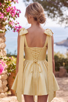 Laden Sie das Bild in den Galerie-Viewer, Buttergelbes A-Line Satin-Perlen-Trim-Mini-Homecoming-Kleid mit Fliege-Schulterriemen